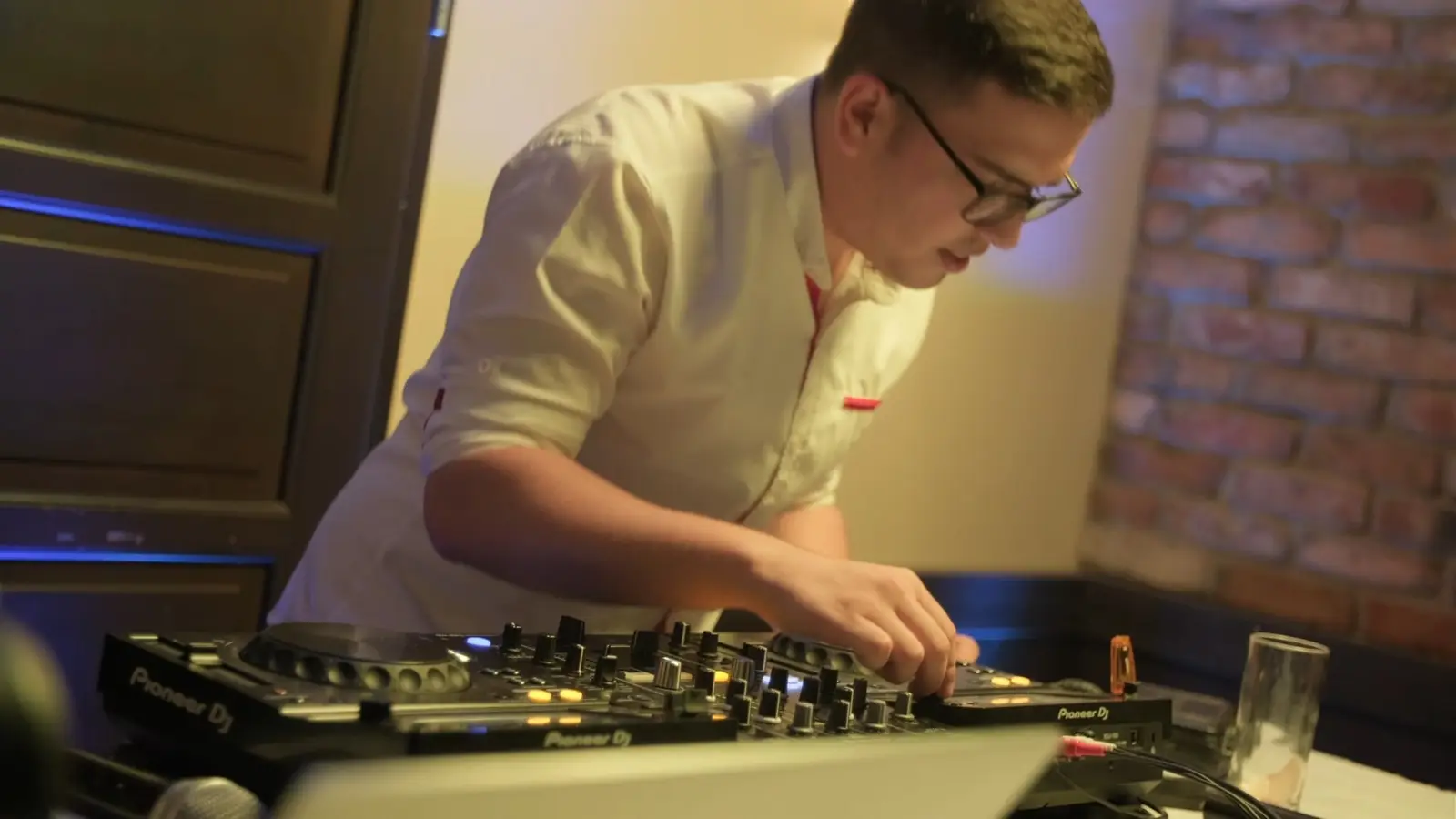 A DJ keze a keverőn, körülötte a buli lendülete