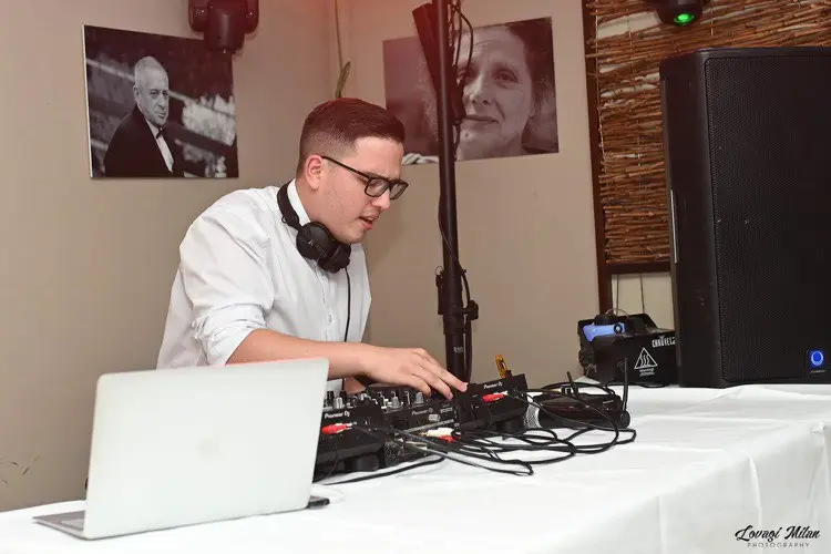 A DJ a laptop és a keverő fölött dolgozik a pult mögött