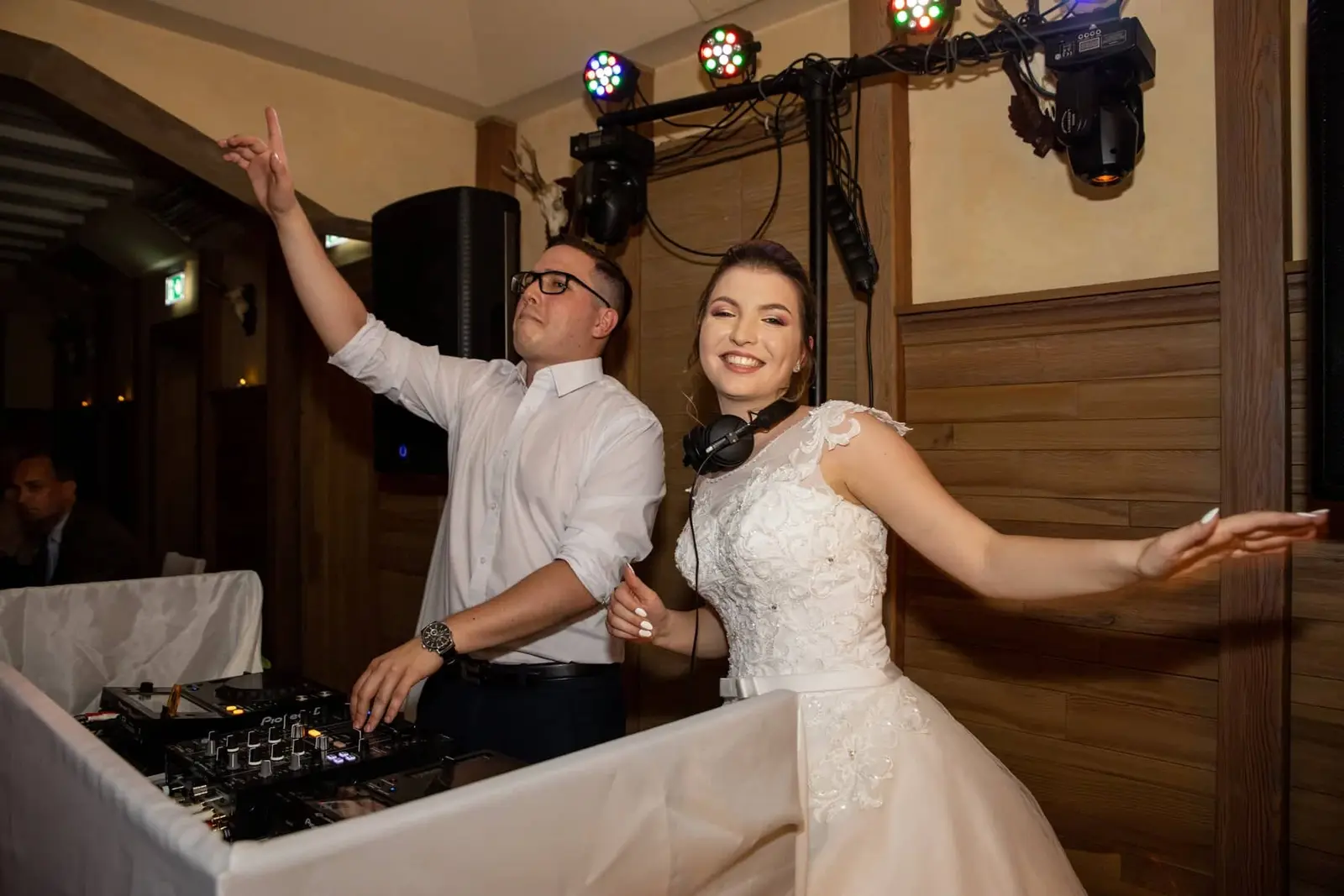 A menyasszony a DJ pultnál táncol a zenésszel az esküvői buli közben