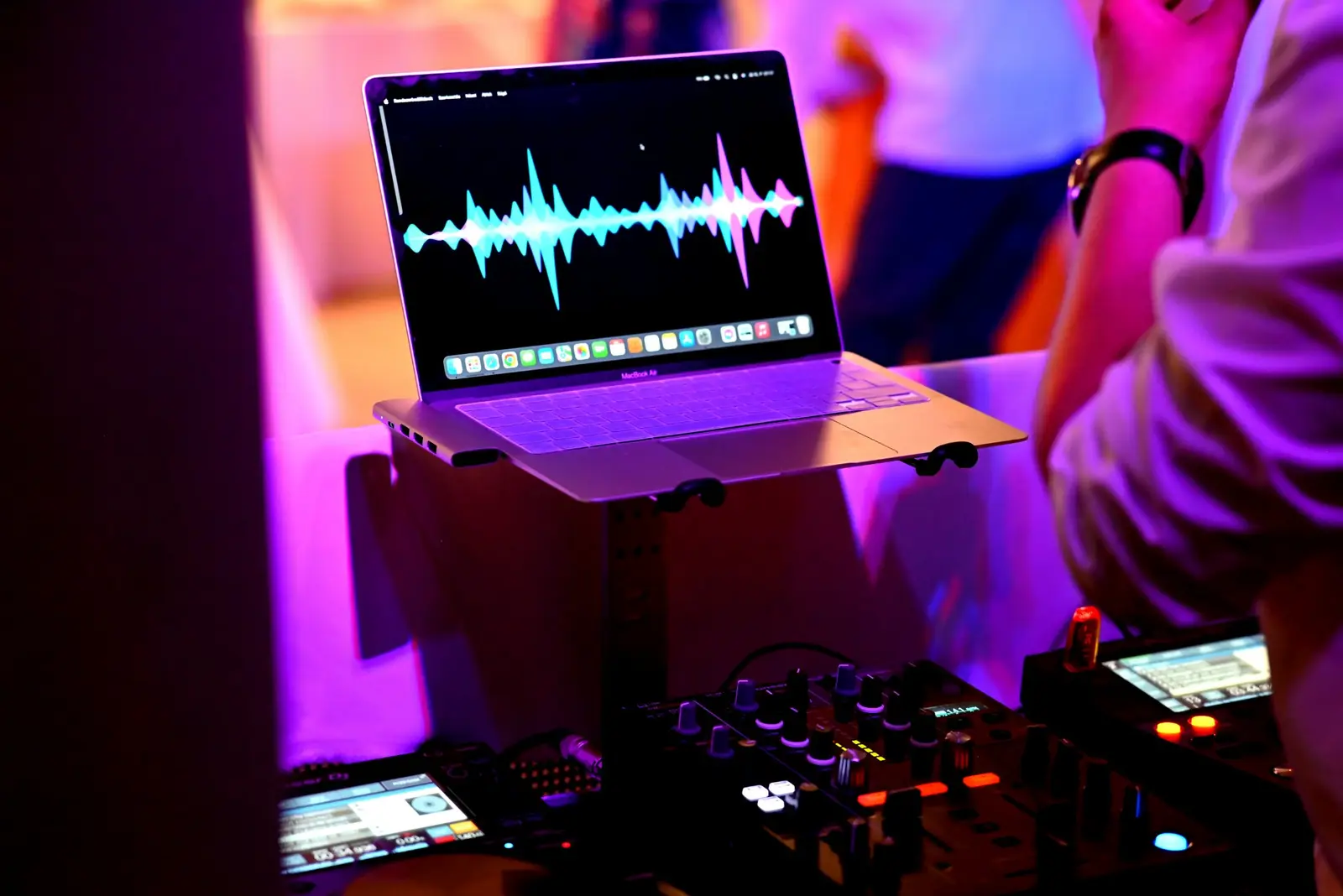 Laptop a zeneszerkesztő programmal a DJ pulton, színes fényekben